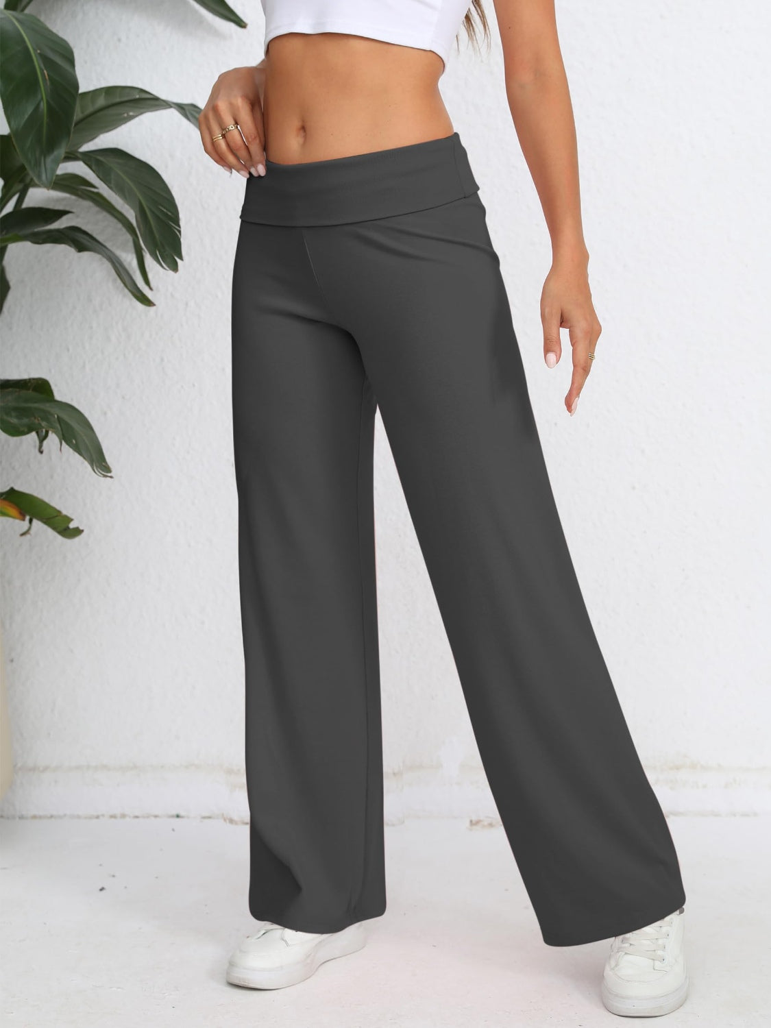 Dark gray palazzo trousers with a fold-over waistband and wide leg, styled with a white top.