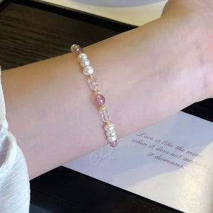 Delicate pearl and crystal bracelet with pink accents and gold beads.