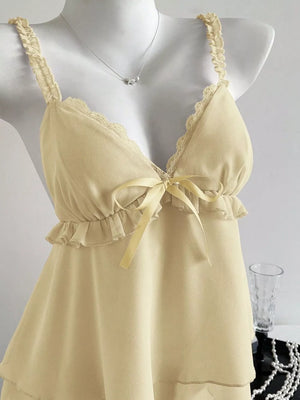 Light yellow camisole with lace trim, ruffled straps, and a bow detail.
