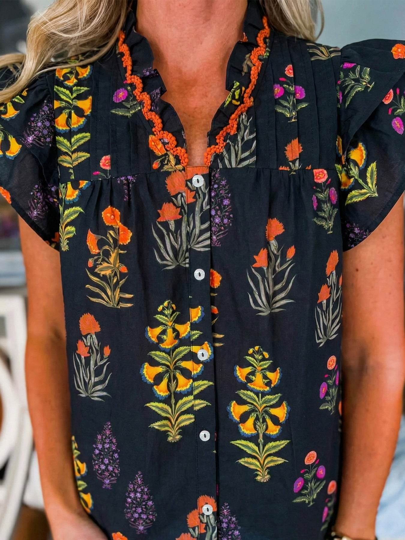 Black floral print maternity shirt with V-neck, button front, and orange frill detail.