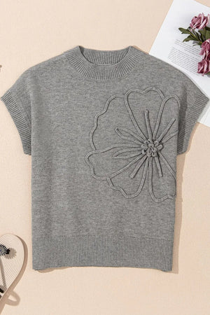 Gray knit blouse with short sleeves and a large embroidered flower detail on the chest.