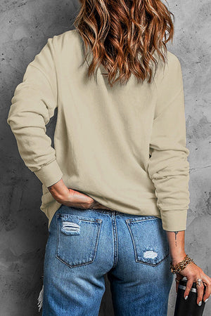 Khaki crewneck sweatshirt with long sleeves, styled with distressed denim jeans.
