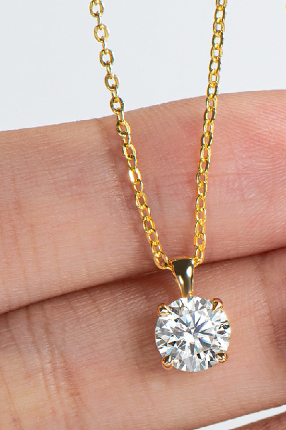 Gold chain necklace with a round solitaire diamond pendant.