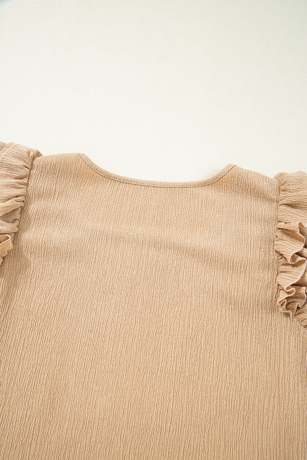 Tan textured blouse with ruffled short sleeves and square neckline.