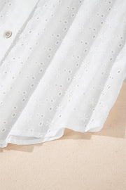 White embroidered eyelet blouse with poet sleeves and a button detail.