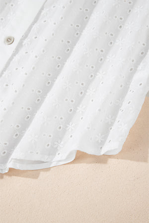 White embroidered eyelet blouse with poet sleeves and a button detail.