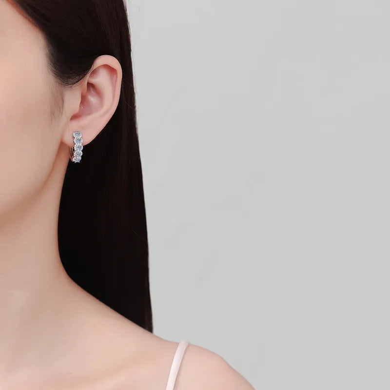 Silver moissanite cluster huggie hoop earrings with five stones.