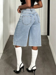 Distressed light wash denim wide-leg shorts with raw hem and distressed details.