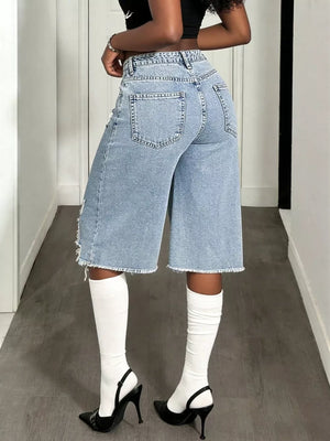 Distressed light wash denim wide-leg shorts with raw hem and distressed details.