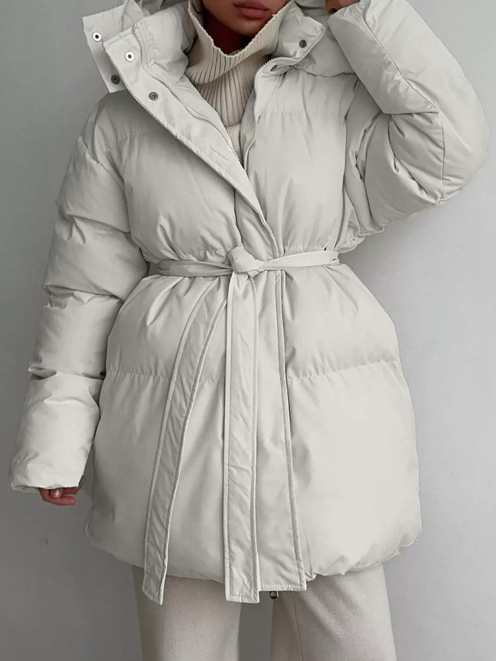 Thick puffer trench coat in ivory white with hood and belted waist.