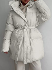 Thick puffer trench coat in ivory white with hood and belted waist.