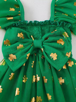 Green tulle baby dress with smocked bodice, gold shamrock print, and large bow detail.