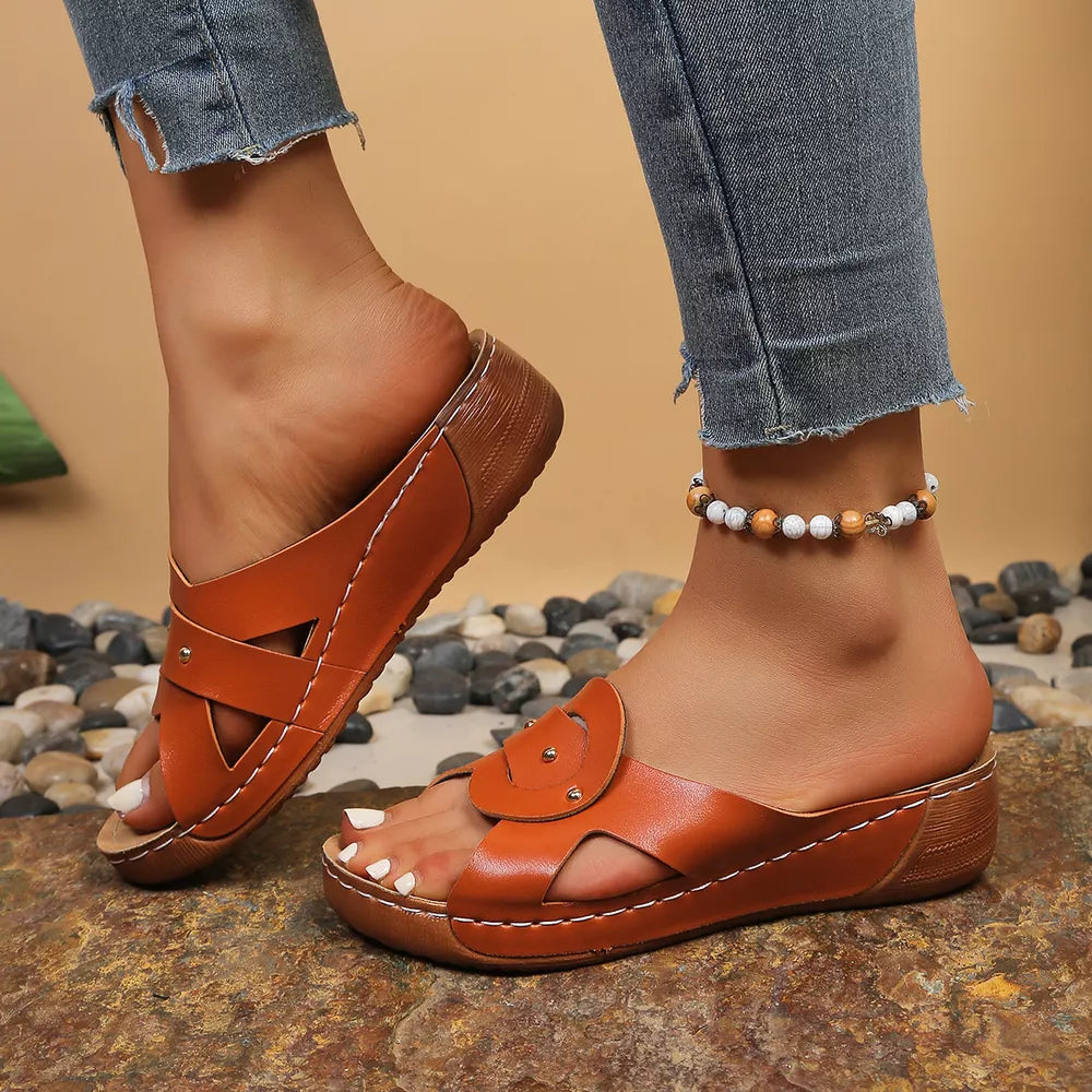 Orange embellished open-toe wedge sandals with decorative straps and white stitching.