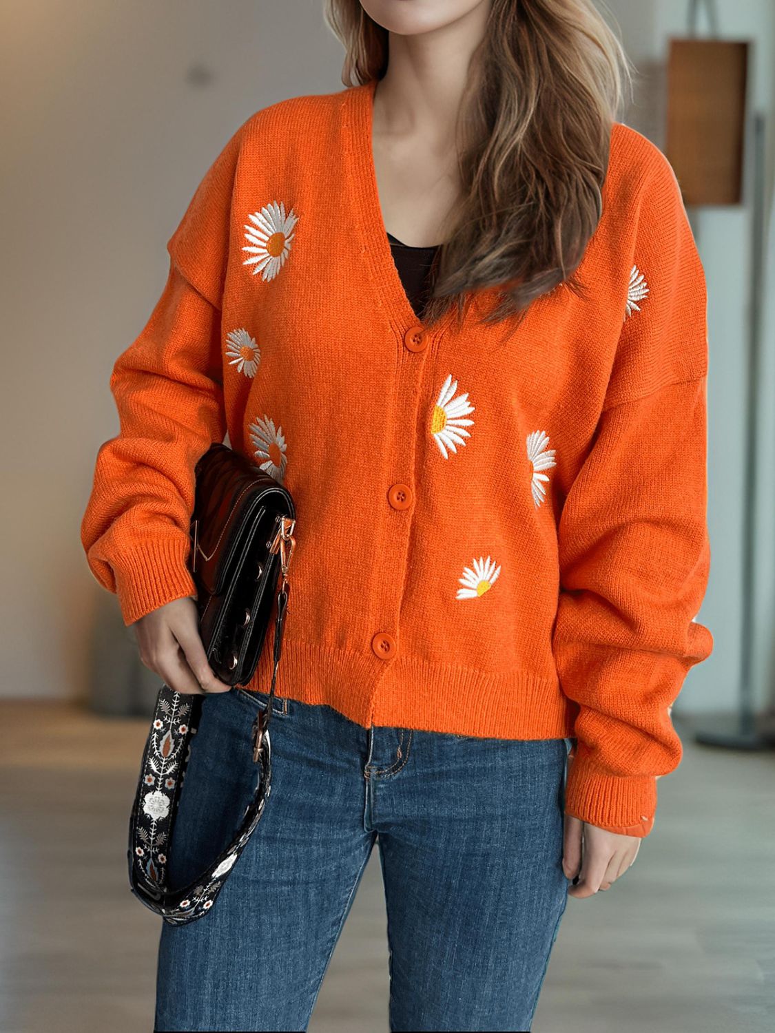 Orange acrylic knit oversized cardigan with daisy embroidery and buttons.
