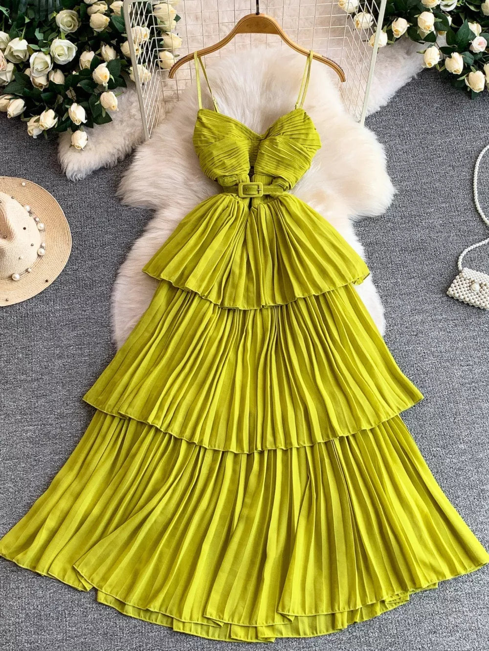 Yellow belted pleated midi dress with spaghetti straps and tiered skirt.