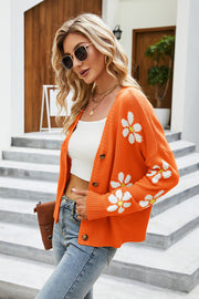 Orange acrylic knit cardigan with white daisy print and button front.