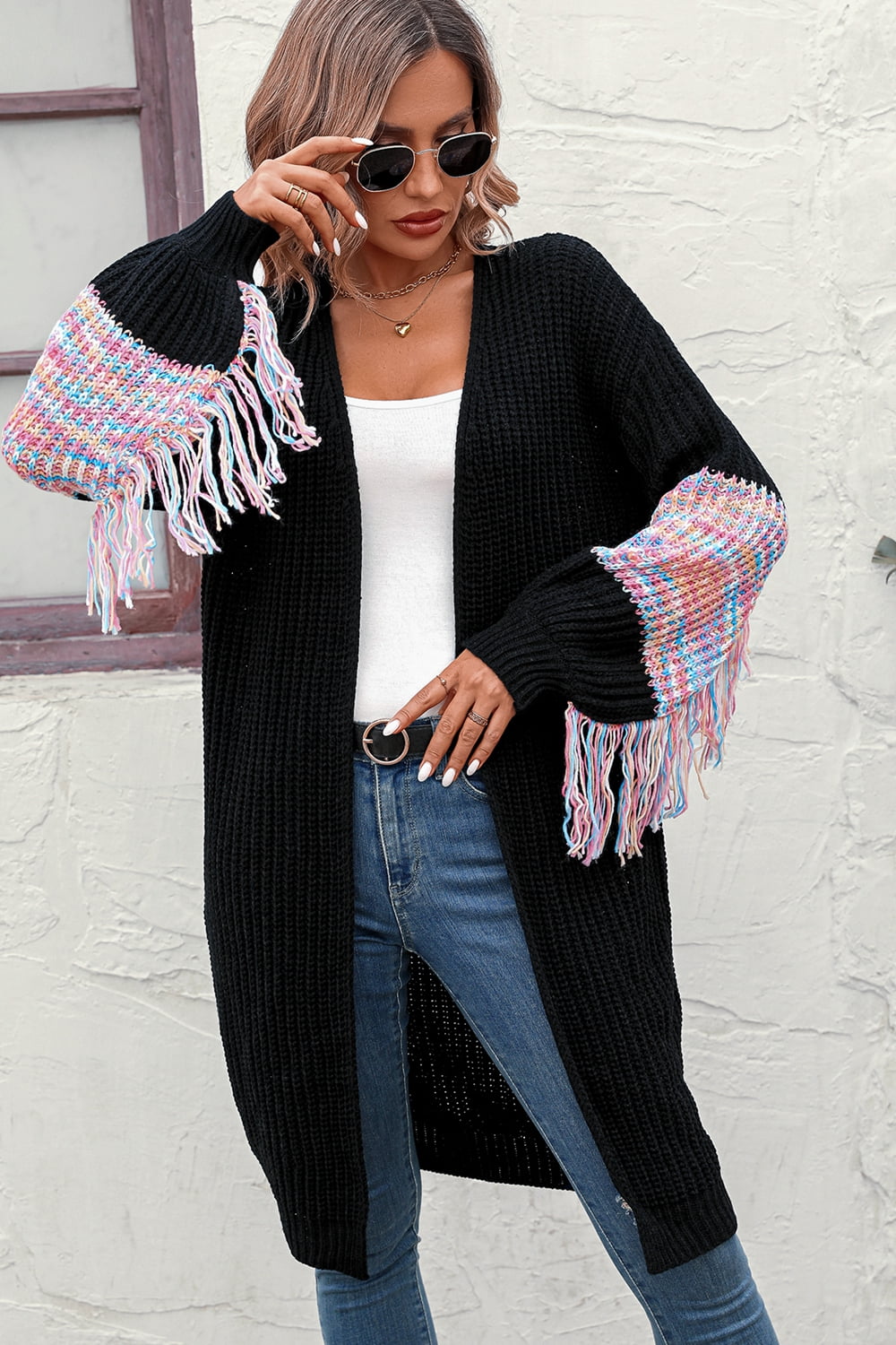 Black knit cardigan with colorful textured sleeve fringe detail and tasseled hem.