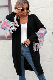 Black knit cardigan with colorful textured sleeve fringe detail and tasseled hem.
