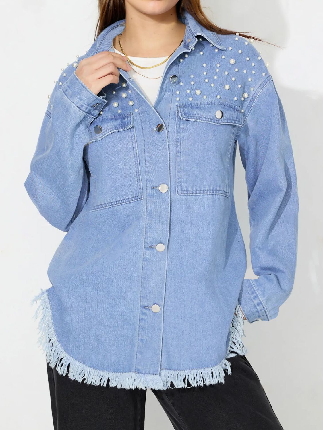 Light wash denim shirt with pearl embellishments on shoulders, frayed hem, and button front.