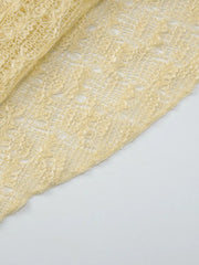 Yellow sheer one-shoulder cropped cardigan with intricate open knit pattern.