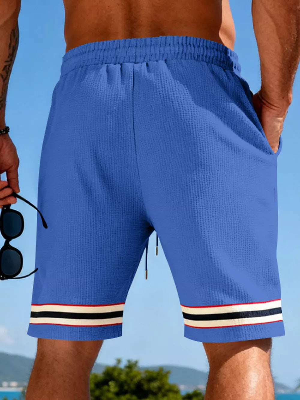 Blue textured knit drawstring shorts with pockets and striped cuffs.