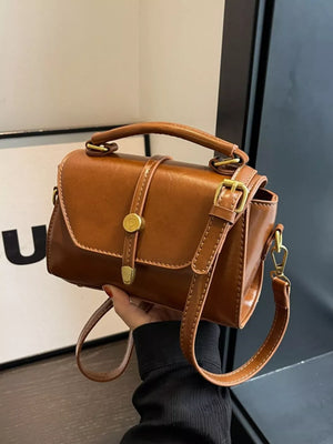 Brown mini crossbody bag in faux leather with gold clasp and adjustable strap.