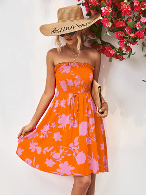 Orange smocked bandeau floral mini dress with drawstring waist and ruffled hem.