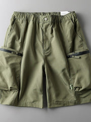 Green relaxed fit cargo shorts with elastic waist, button closure, and zippered pockets.