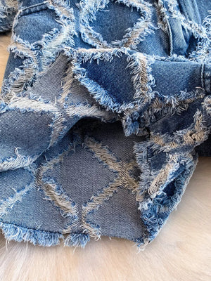 Distressed denim shorts with frayed patchwork design and raw hem.