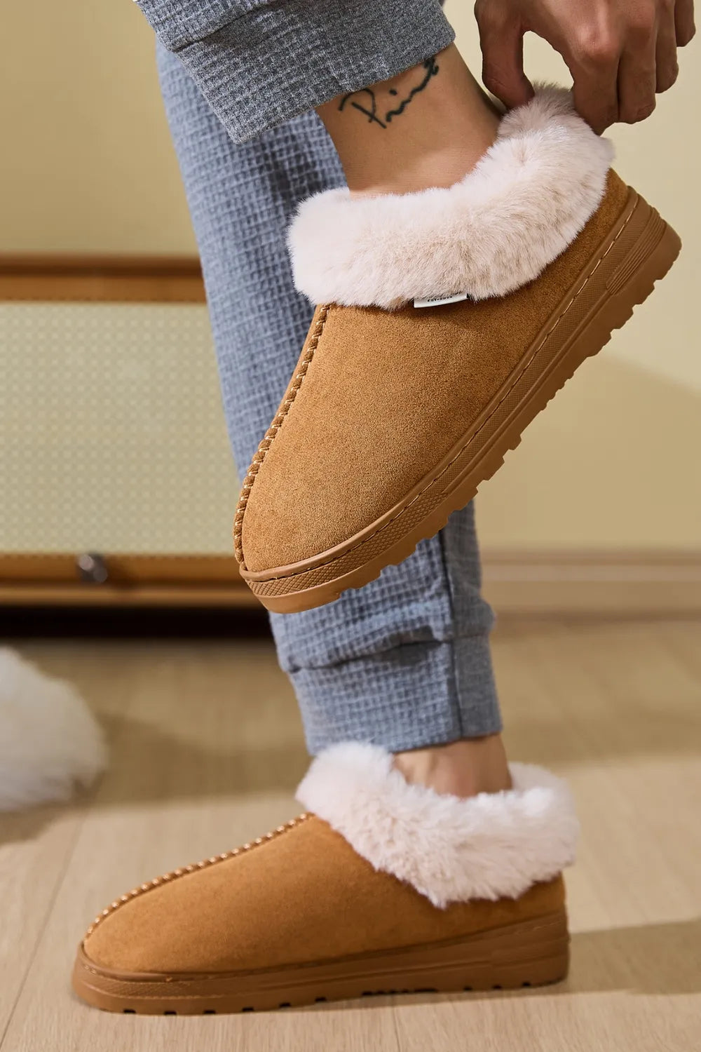 Caramel suede slippers with plush shearling trim and contrast stitching.