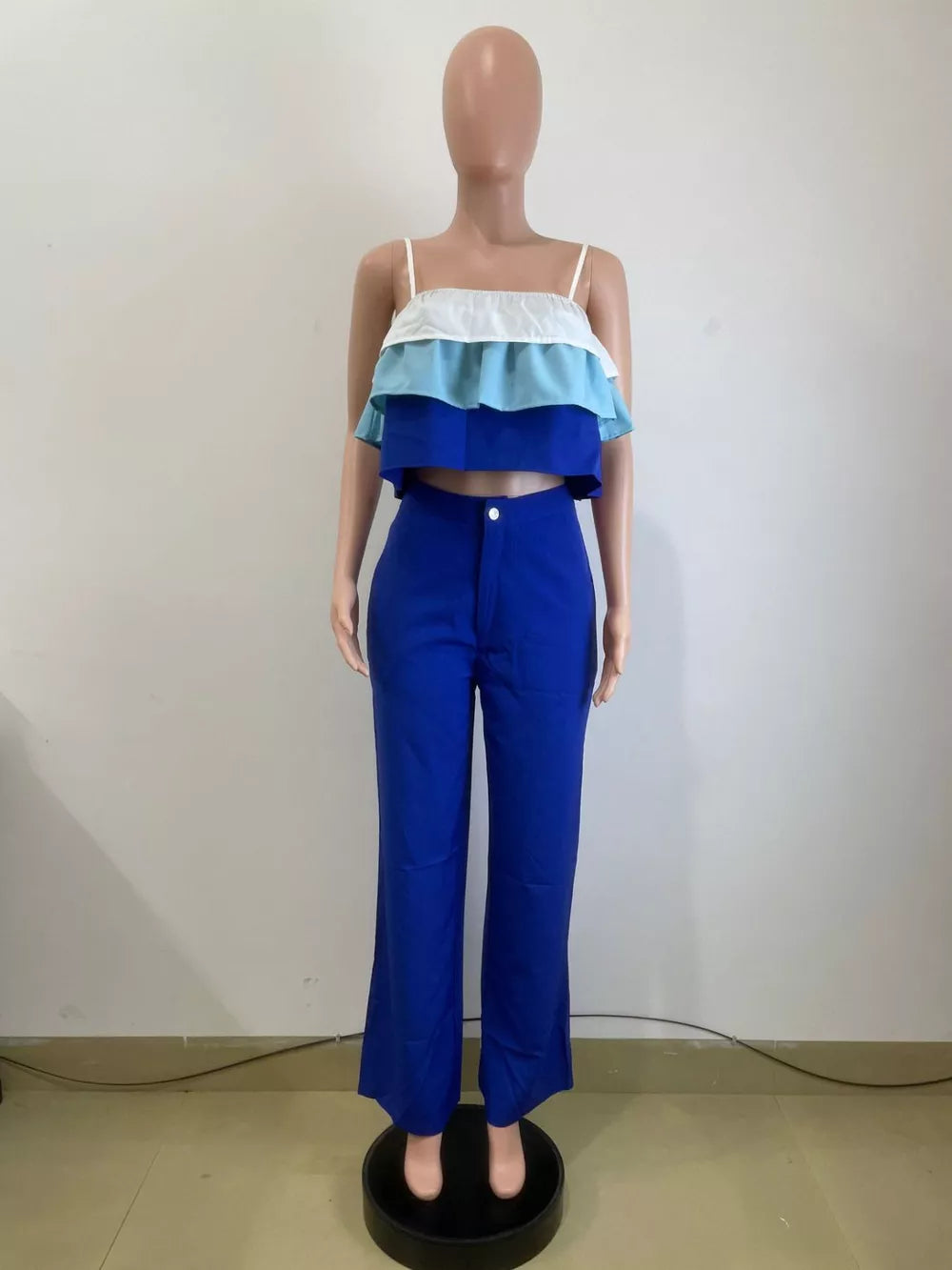 Chic layered ruffle crop top set in blue with white and light blue tiers, paired with wide-leg pants.