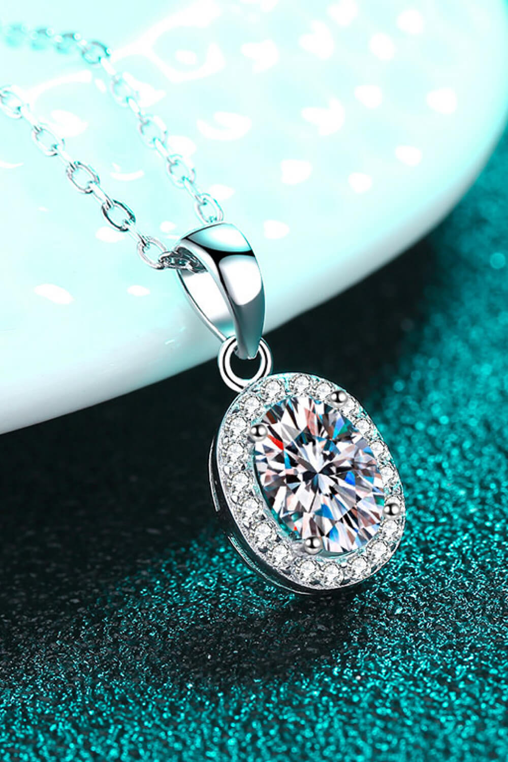 Silver halo moissanite pendant necklace with oval-cut center stone and diamond accent halo.