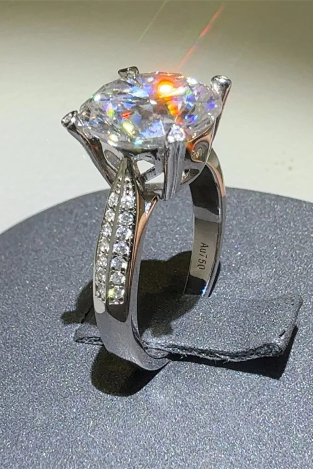 Silver moissanite engagement ring with pavé band and round center stone.