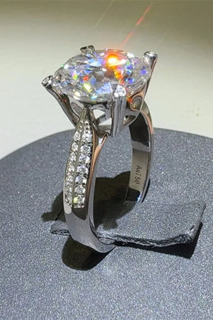 Silver moissanite engagement ring with pavé band and round center stone.