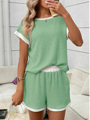Light green ribbed knit two-piece set with white trim, short sleeves, and elastic waistband shorts.