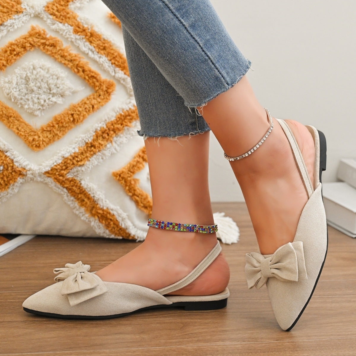Beige slingback flats with bow detail and pointed toe, styled with anklets.