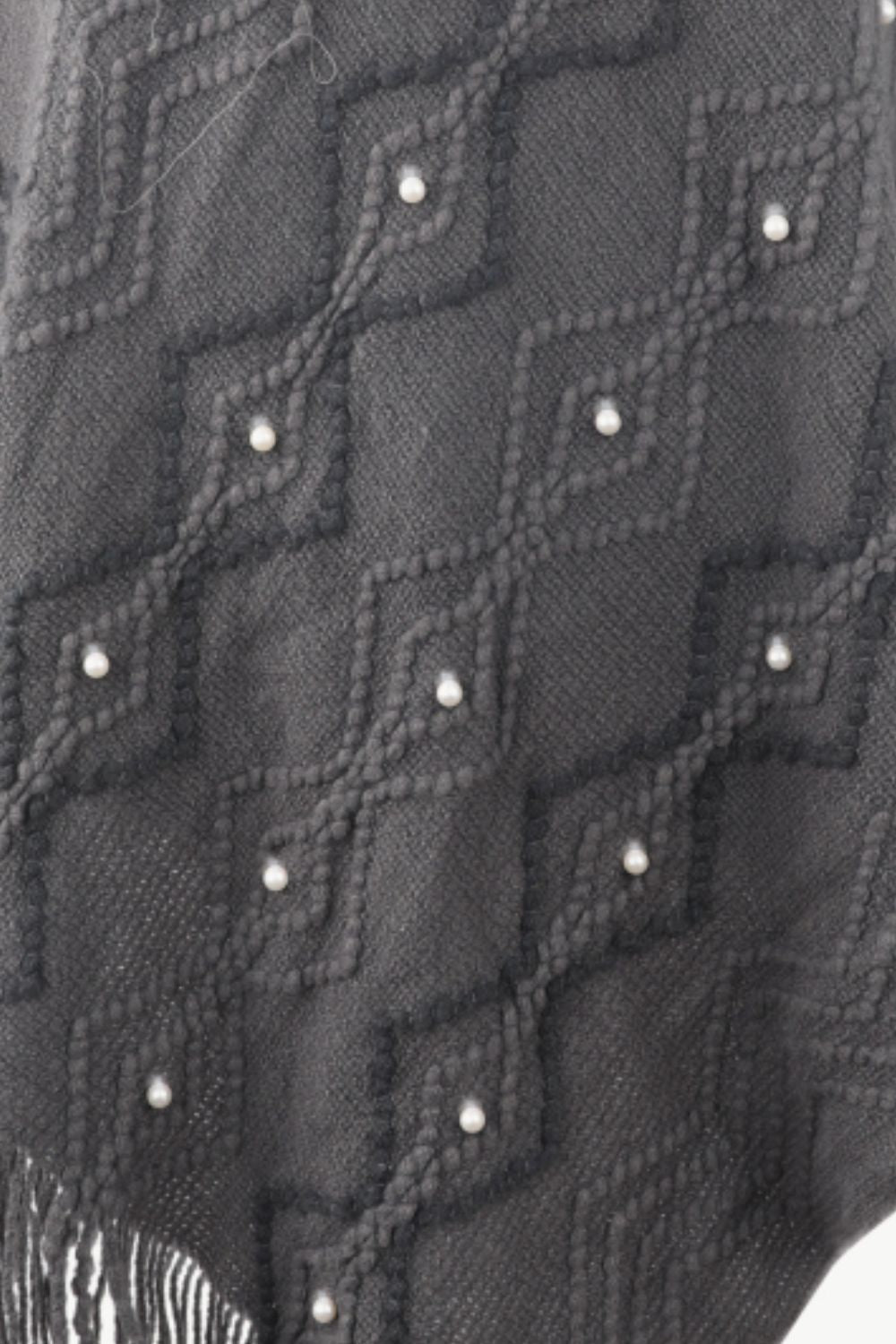 Charcoal knit poncho with geometric diamond pattern and pearl embellishments, fringed hem.
