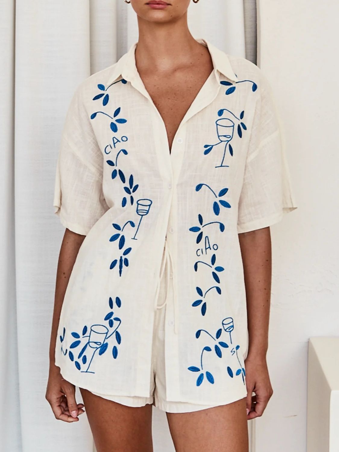 Cream linen co-ord set with blue embroidered floral and wine glass motif.