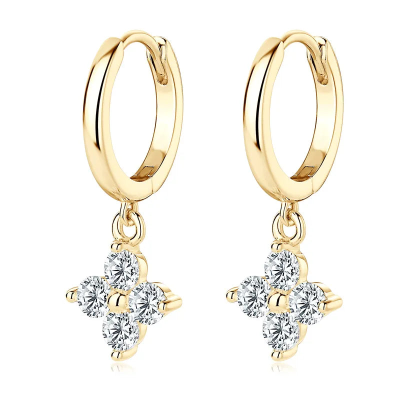 Gold huggie hoop earrings with dangling clover charms set with clear crystals.