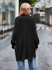 Black open-stitch waffle knit duster cardigan with side slits and long sleeves.