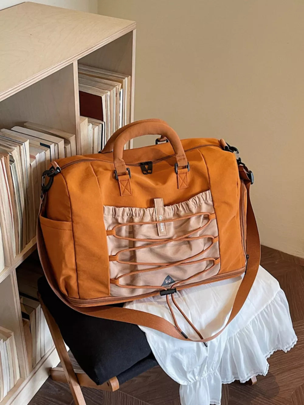 Orange nylon duffel bag with bungee cord detail and tan accents.
