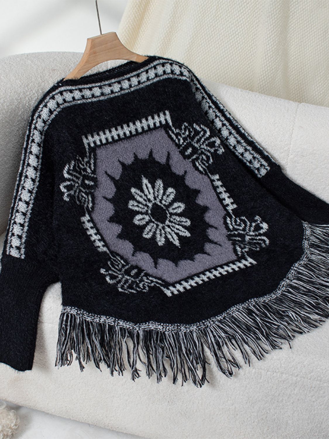 Black acrylic knit poncho with Aztec motif and fringe detail.