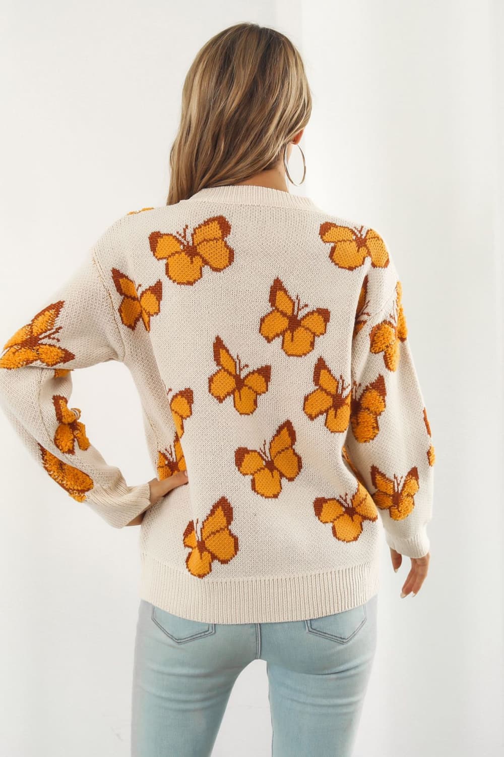Beige acrylic knit crewneck pullover sweater with allover orange butterfly motif.