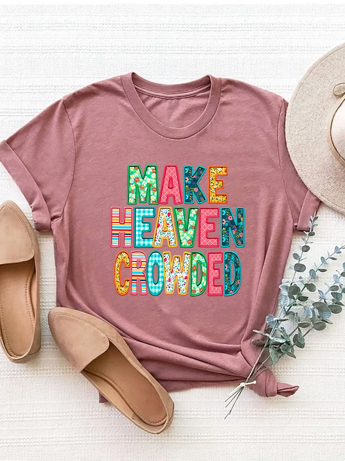 Dusty pink t-shirt with textured "Make Heaven Crowded" lettering in colorful patterns.