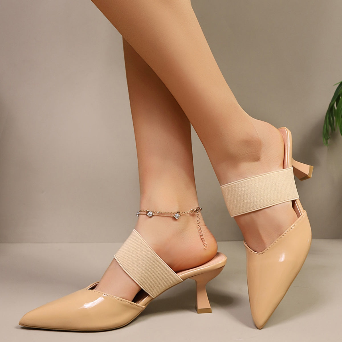 Apricot pointed toe mules with elastic strap and sculpted mid-heel.