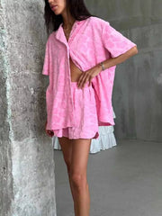 Pink textured floral button-up shirt and shorts set with short sleeves.