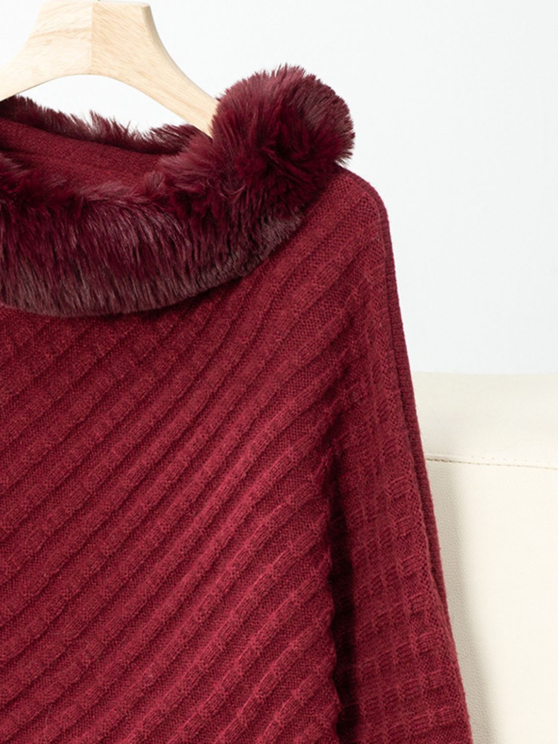 Burgundy knit poncho with faux fur trim and diagonal ribbing detail.