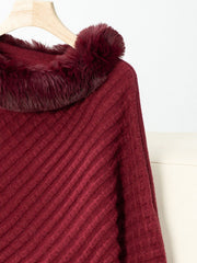 Burgundy knit poncho with faux fur trim and diagonal ribbing detail.