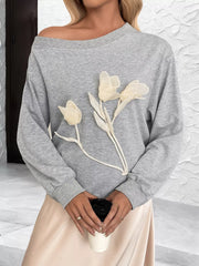 Gray boat neck sweater with delicate floral applique detail.