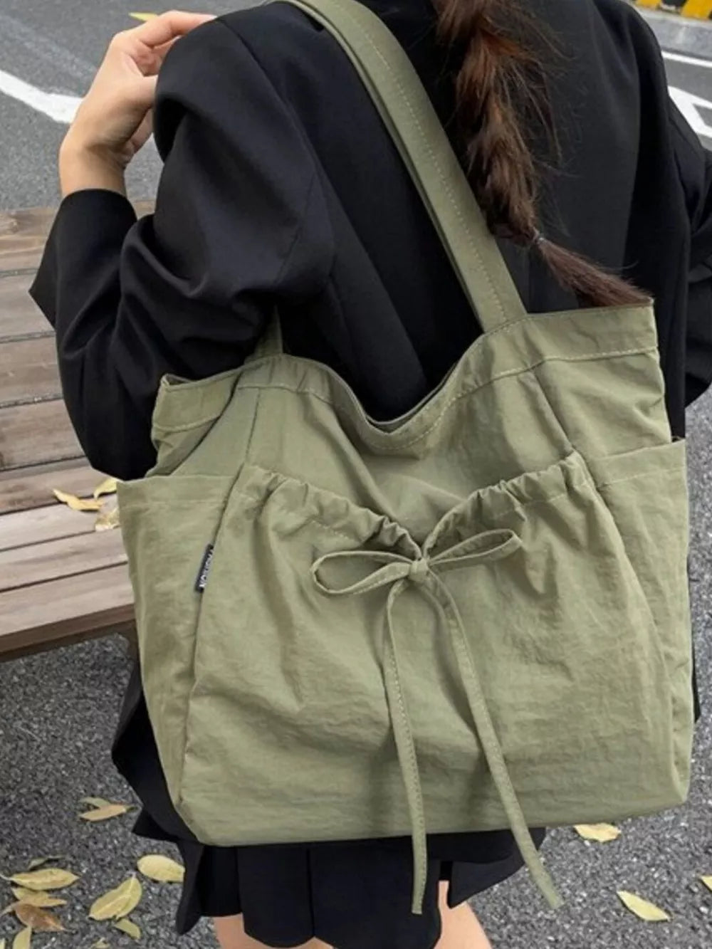 Olive green nylon tote bag with drawstring closure and bow detail.